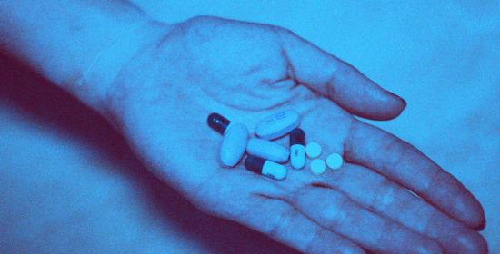 blue picture of a hand holding pills