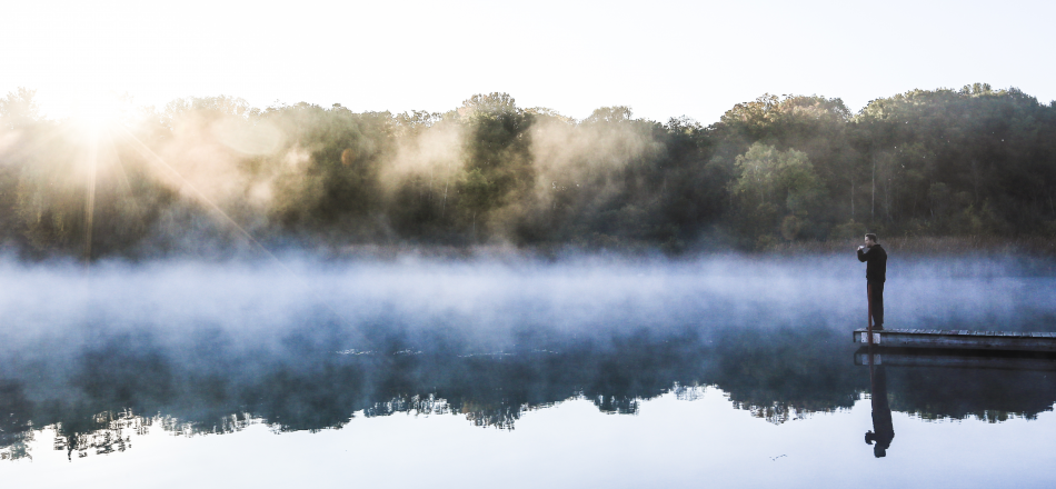 man looking over calm lake