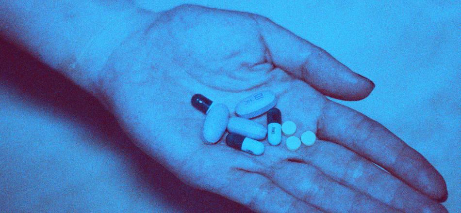 blue picture of a hand holding pills