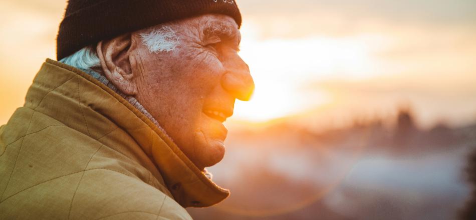 old man outside with sun shining behind him