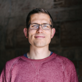 man smiling wearing glasses and a t-shirt