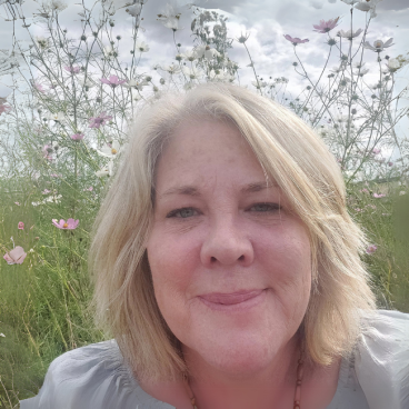 A photograph of Trudie with flowers and grass in the background